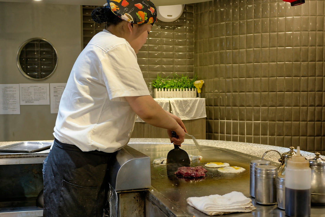 A man in a kitchen cooking food on a grill
