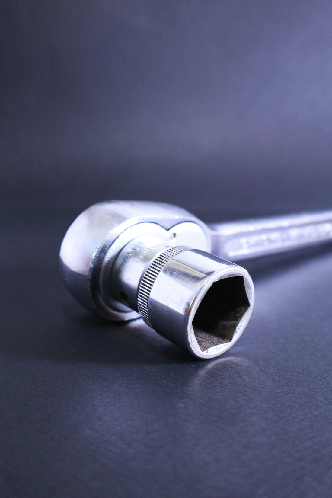 A socket wrench rests against a dark background.
