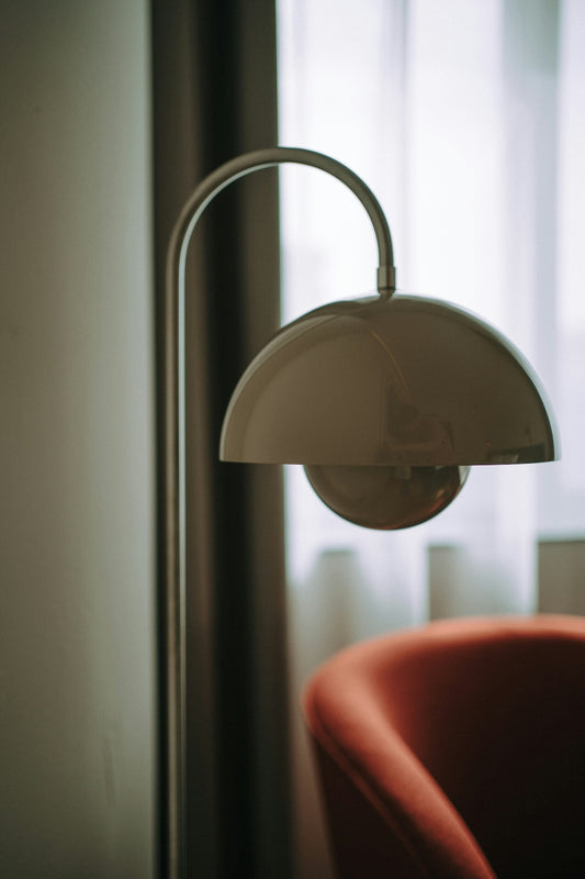 A modern floor lamp beside an orange armchair