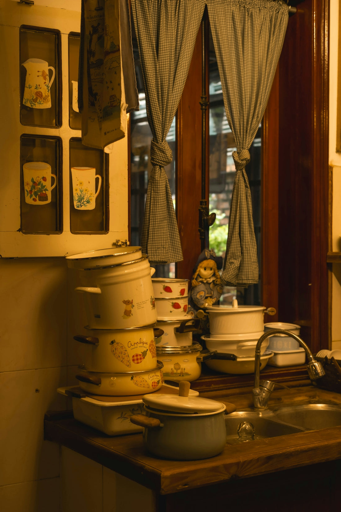 Stack of vintage pots and pans by a kitchen sink