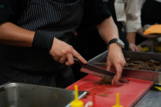 Chef chopping food on a red cutting board.