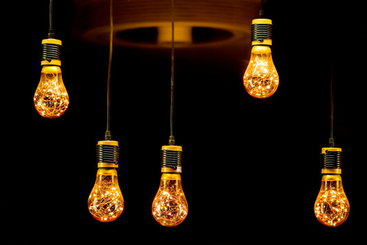 Five decorative edison bulbs hanging against black