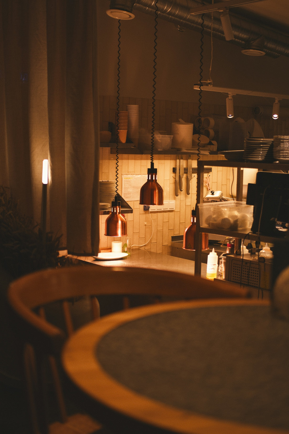 Warmly lit kitchen with pendant lights and wooden chair