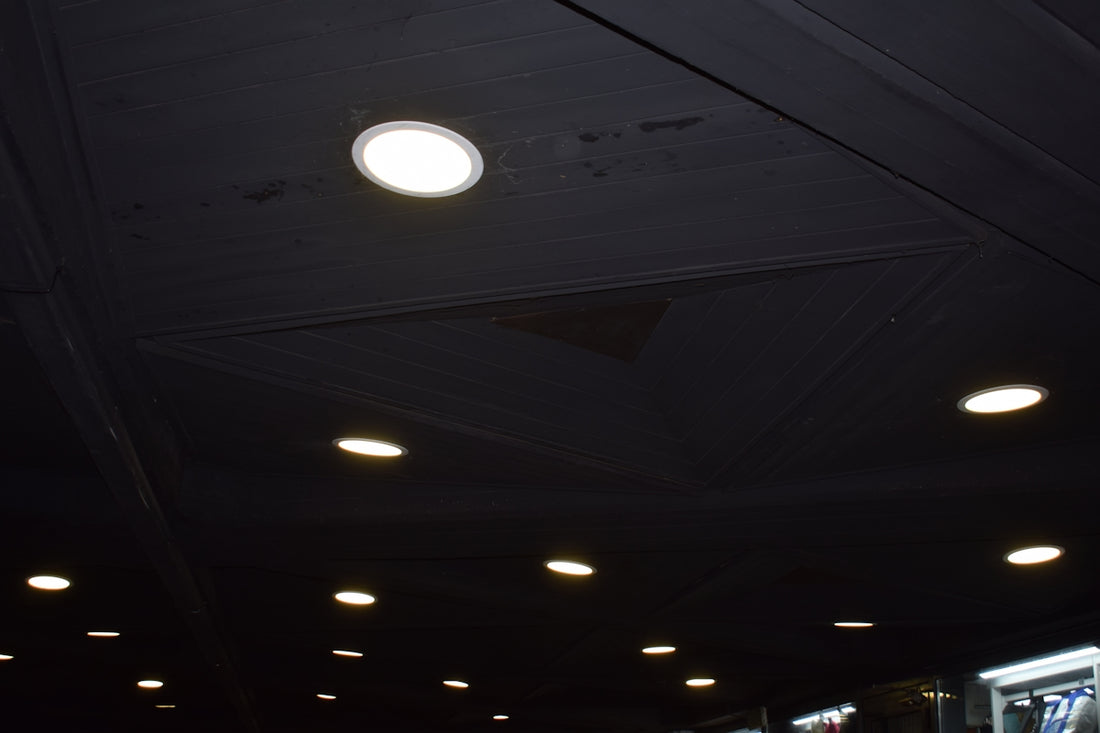 Recessed ceiling lights illuminating a dark space.