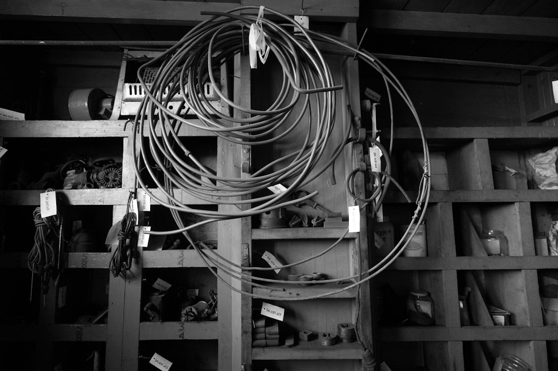 Coiled wires hang from a shelf in a workshop.