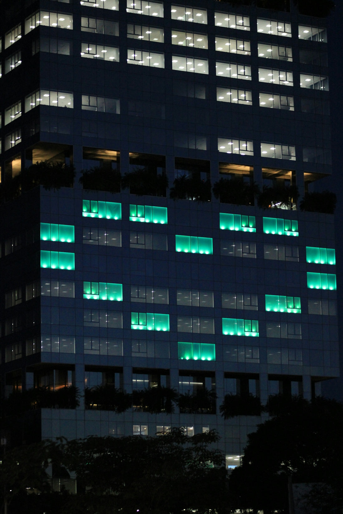 Modern skyscraper illuminated with green lights at night