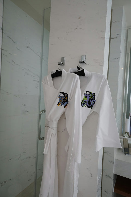 Two white robes hanging on hooks in a bathroom.