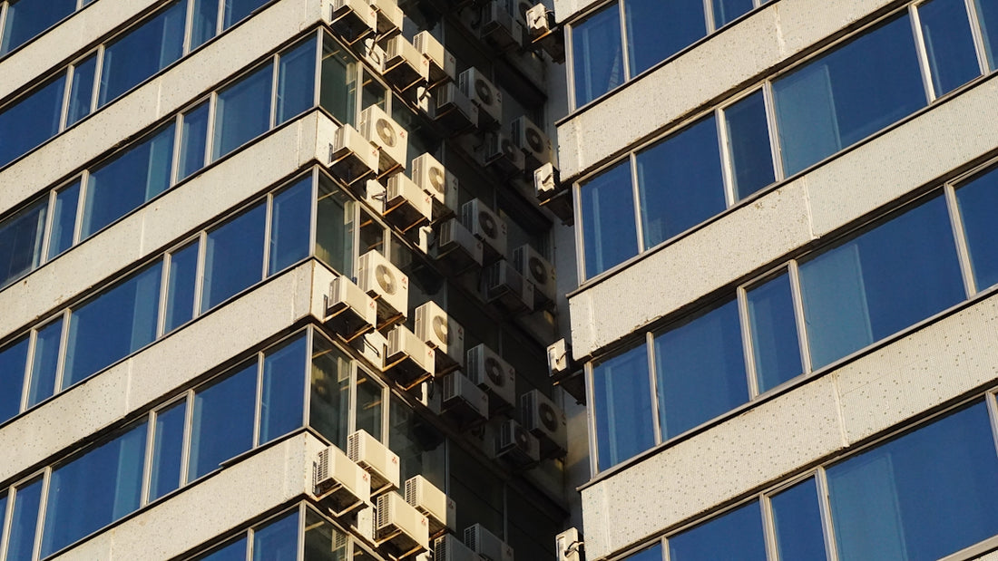 Modern building exterior with many windows and ac units.