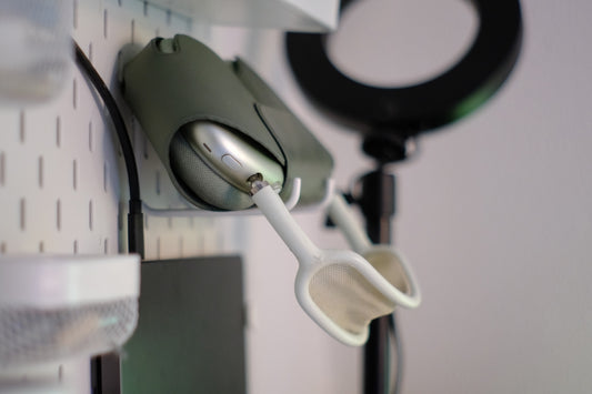 Green apple airpods max headphones hanging on a white pegboard.