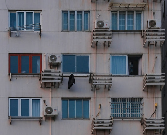 Old apartment building facade with numerous windows and air conditioners.