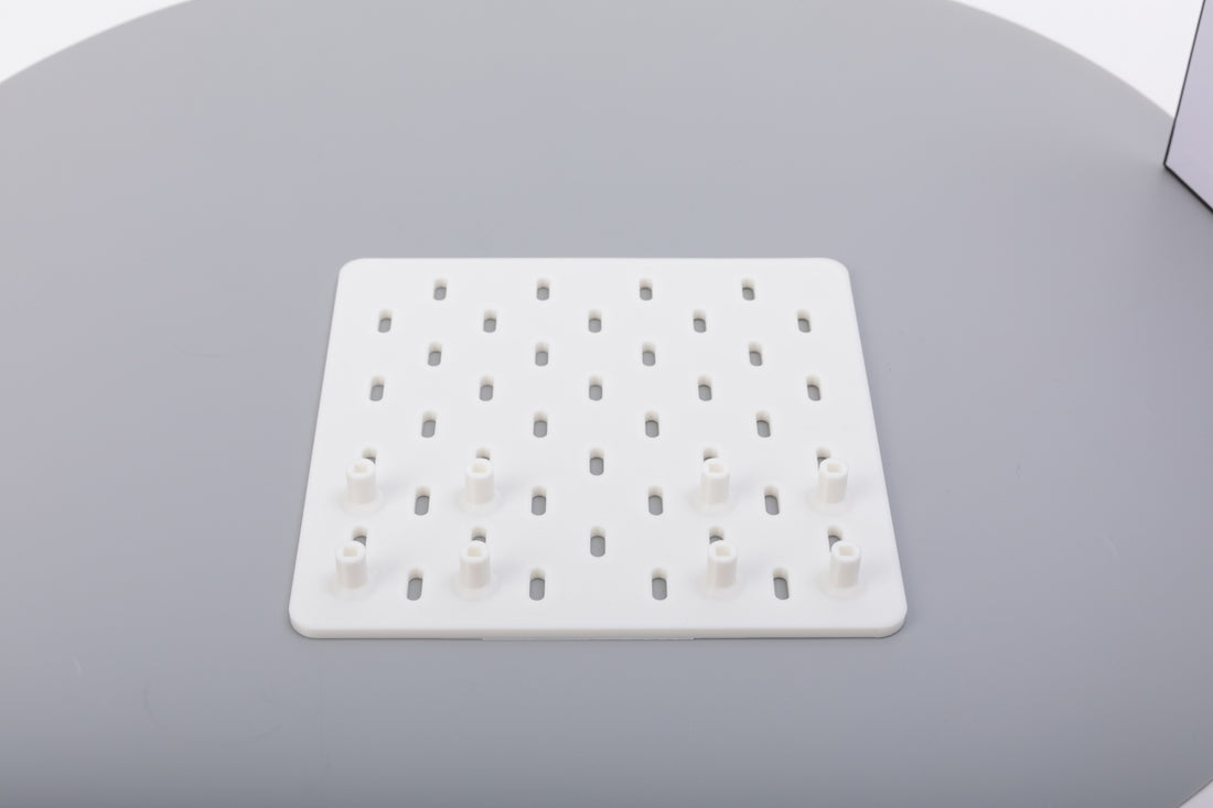 A white pegboard with some pegs on a gray surface.