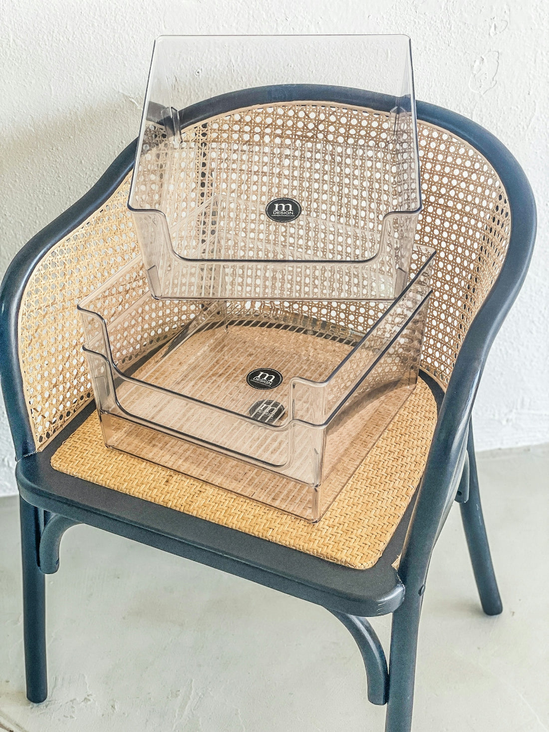 Two clear plastic organizers stacked on a cane chair.