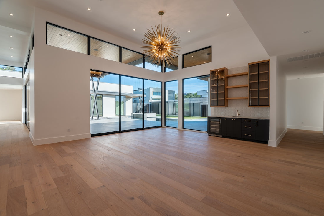 Spacious modern room with wood floors, large windows, and bar.