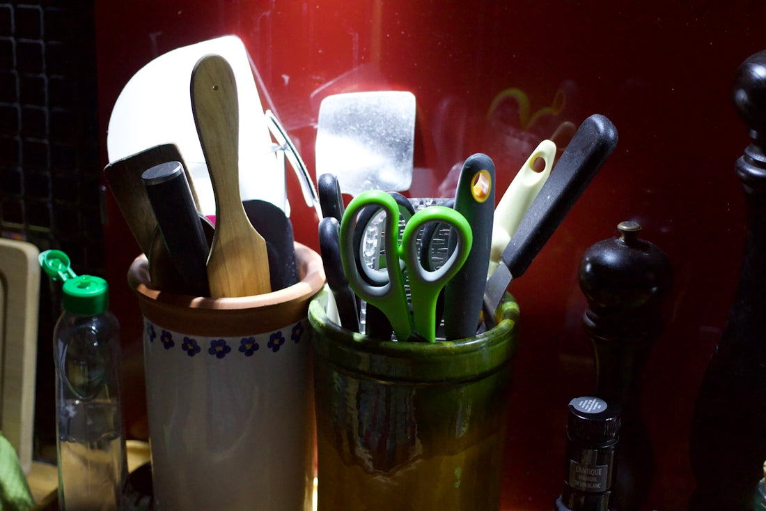 Kitchen utensils including spoons, knives, and scissors in containers.