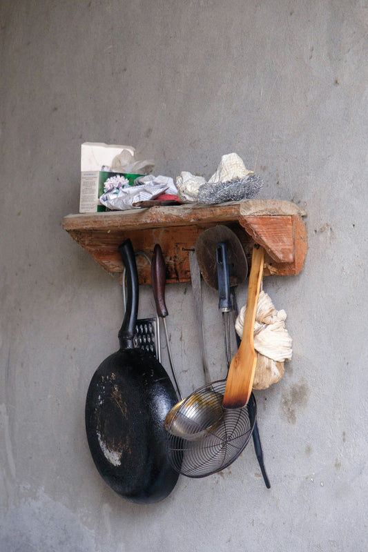Various kitchen tools hanging from a rustic wooden shelf