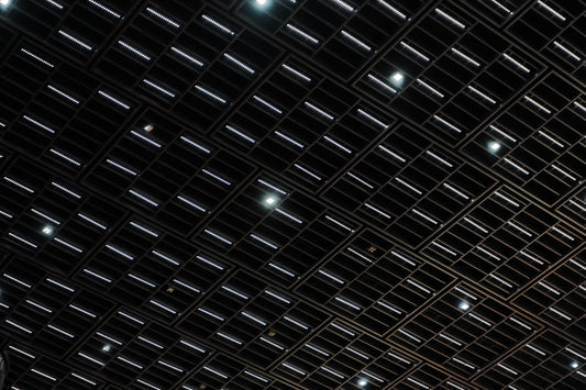 Dark ceiling with grid of rectangular and circular lights.