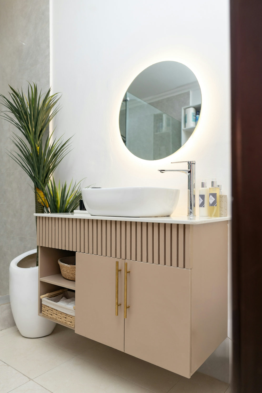 Modern bathroom vanity with sink, illuminated mirror, and green plant.