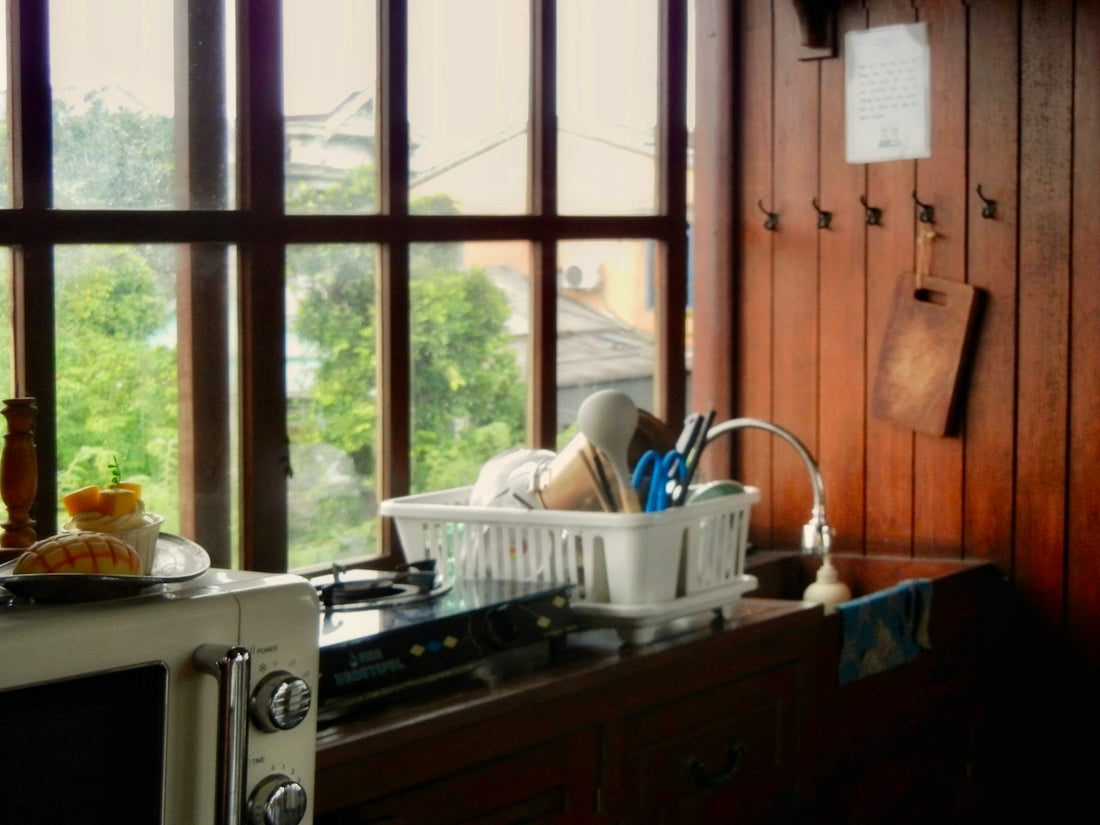 A white microwave and dish rack on a wooden counter in a kitchen