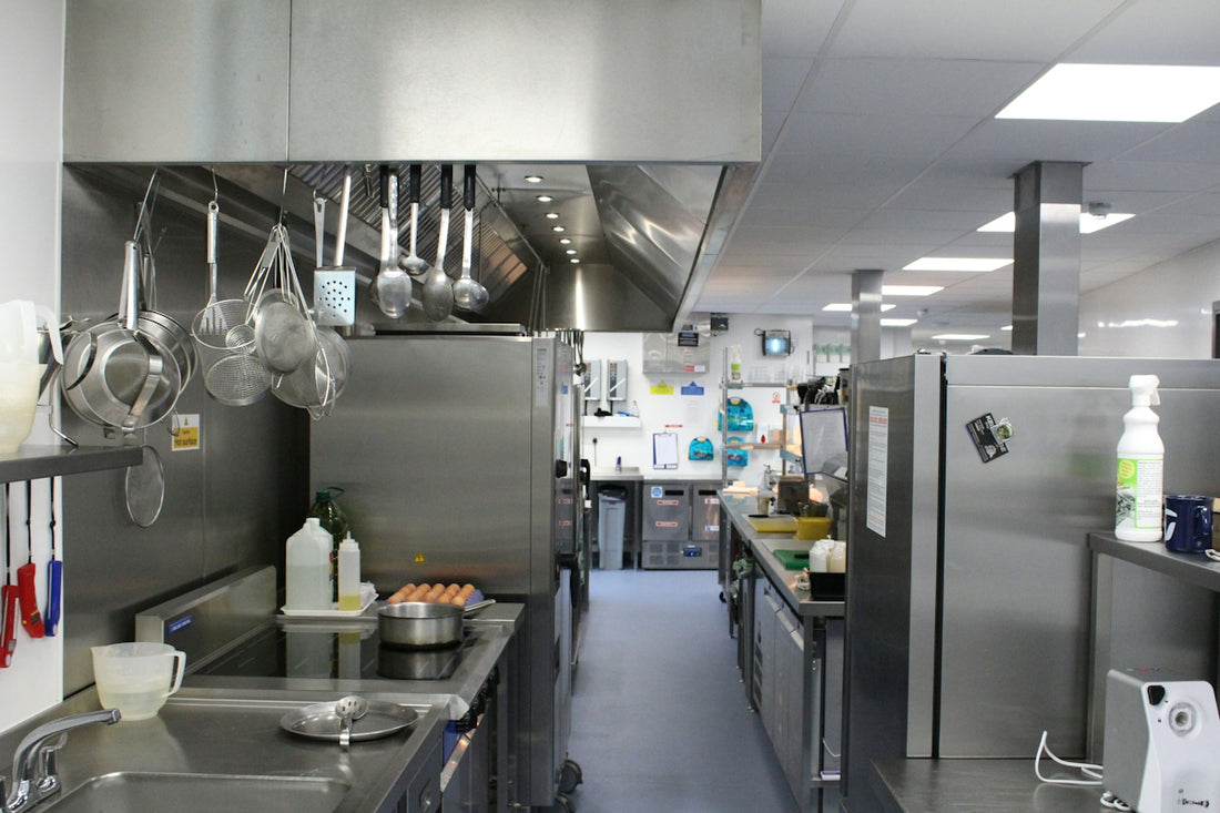 A commercial kitchen with stainless steel appliances, hanging cookware, and a central aisle